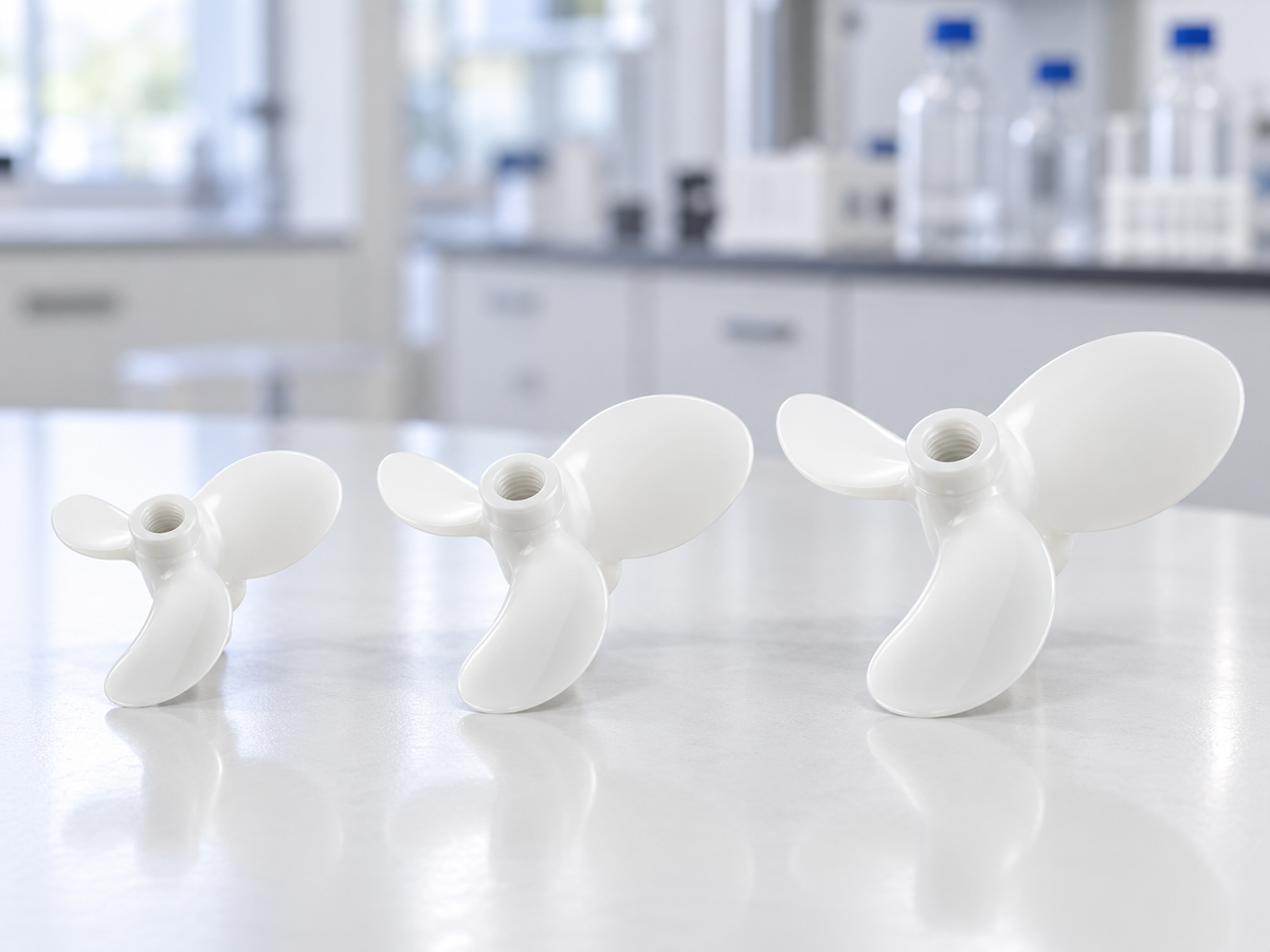 Three white Purisan™ PVDF mixing impellers in different sizes on a laboratory bench.