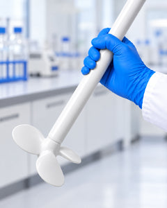 Gloved hand holding a white Purisan™ PVDF mixing impeller and shaft in a laboratory.