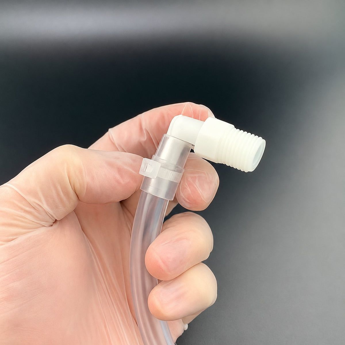 Strong-Ty® natural PVDF cable tie securing tubing to a bioprocessing fitting in a gloved hand.